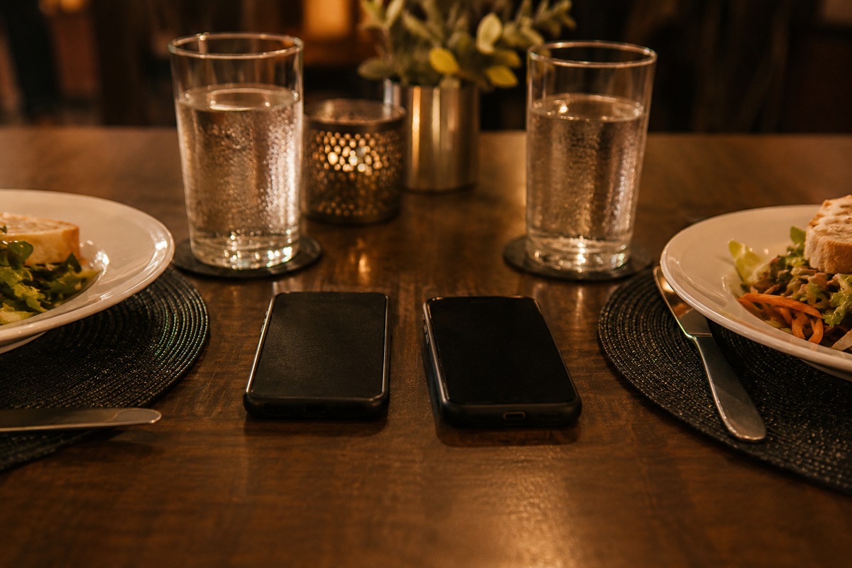 Two phones placed face down between empty seats at a dinner table